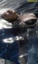 A woman in a black bathing suit floating in a pool.