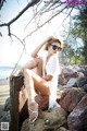 A woman sitting on a rock on the beach.