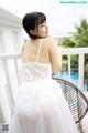 A woman in a white dress sitting on a balcony.