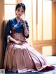 A woman in a blue and pink dress sitting on a window sill.