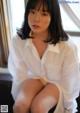 A woman in a white shirt sitting on a window sill.