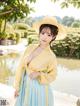 A woman in a yellow and blue dress and a straw hat.