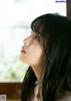 A woman with long black hair looking out a window.