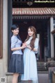 A couple of women standing next to each other in front of a building.